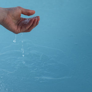 Closeup of a person's hand picking up ice out of the blue water
