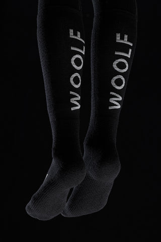 Image of a person's legs from the back wearing the Torset Thin Sock in black, against a black background