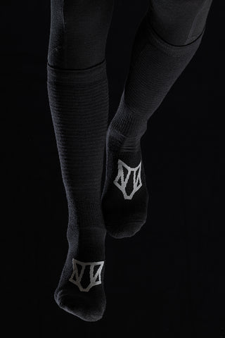 Image of a person's legs wearing the Torset Thin Sock in black, against a black background