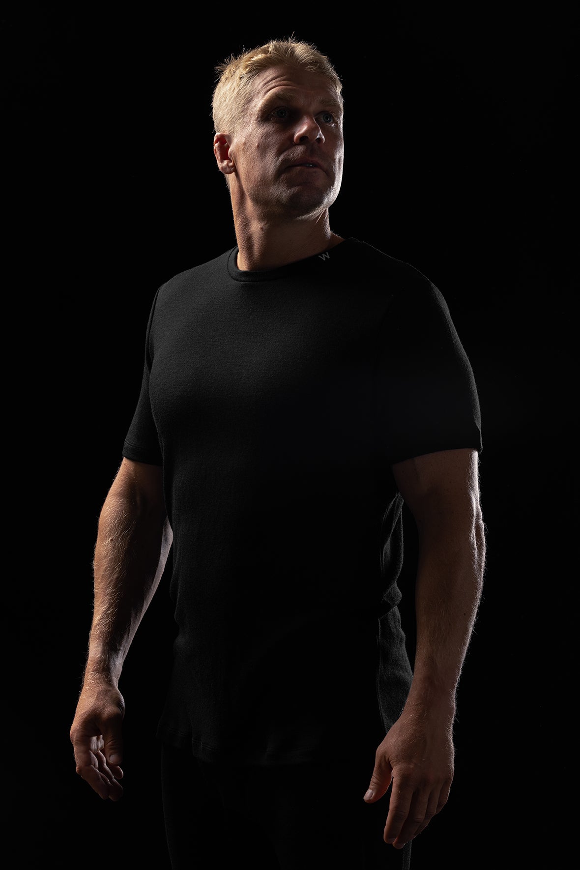 Image of a man wearing the Heisen Performance Tee in black, standing against a black background
