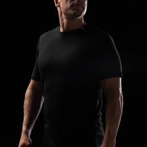 Image of a man wearing the Heisen Performance Tee in black, standing against a black background